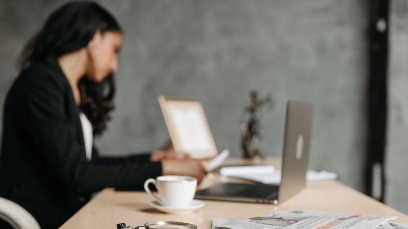 A woman in a business suit working at a desk with a laptop and papers in an office., tags: eure rechtliche - pexel